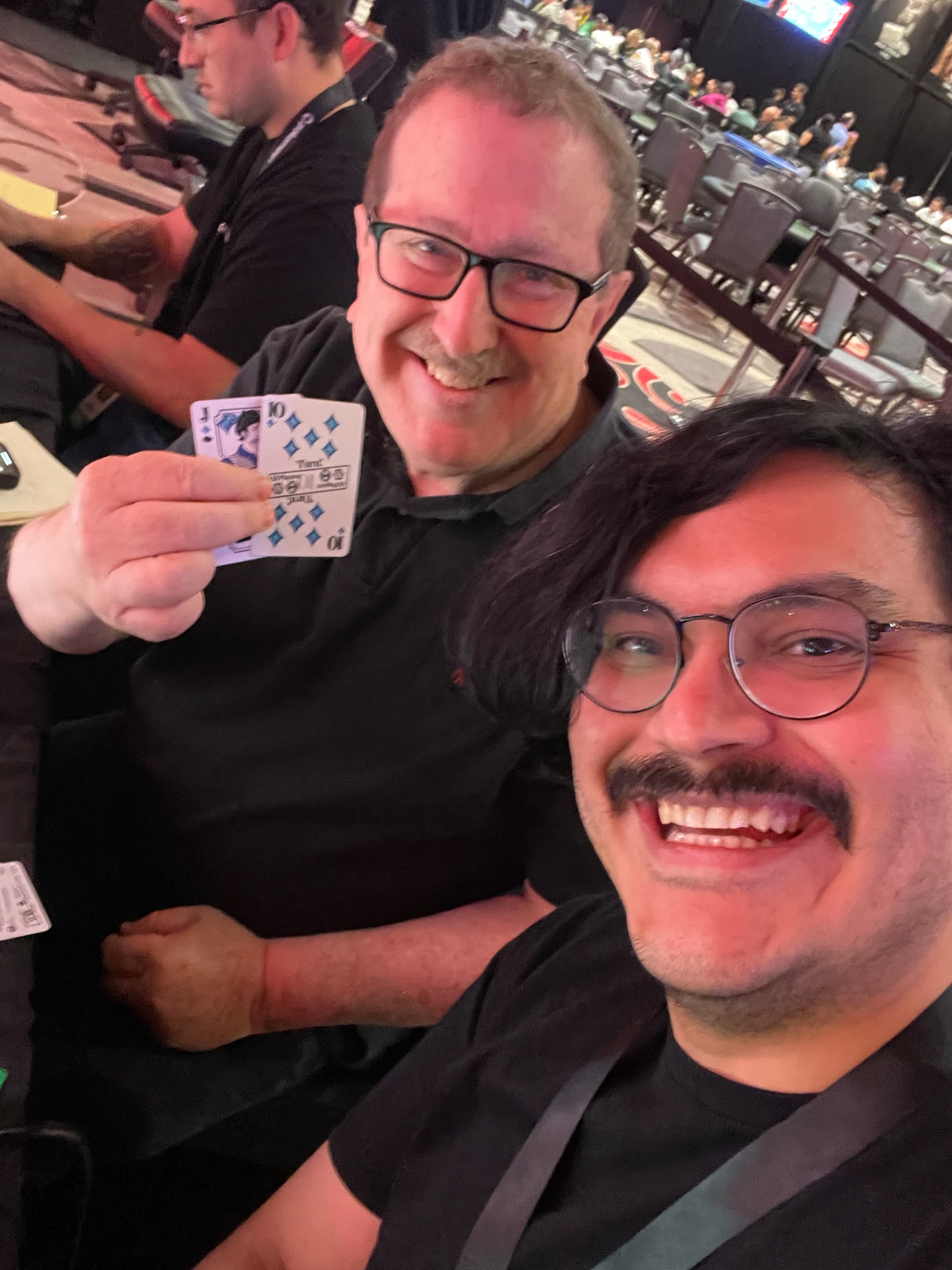 Claudio Elizalde, known as AudioCloud and creator of 'Hold 'Em For Dear Life,' holding a deck of cards and smiling next to Norman Chad, legendary poker commentator